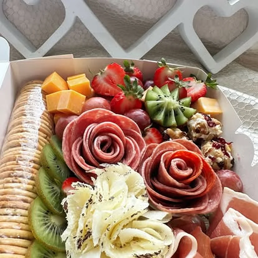 Caja de charcutería de A&K Paellas con rosas de salami, cubos de queso, fresas, uvas, kiwi y galletas