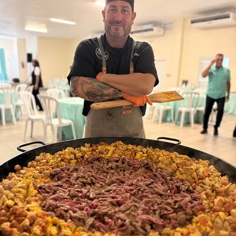 El chef Ángel con la tabla A&K frente a una paella grande en un evento